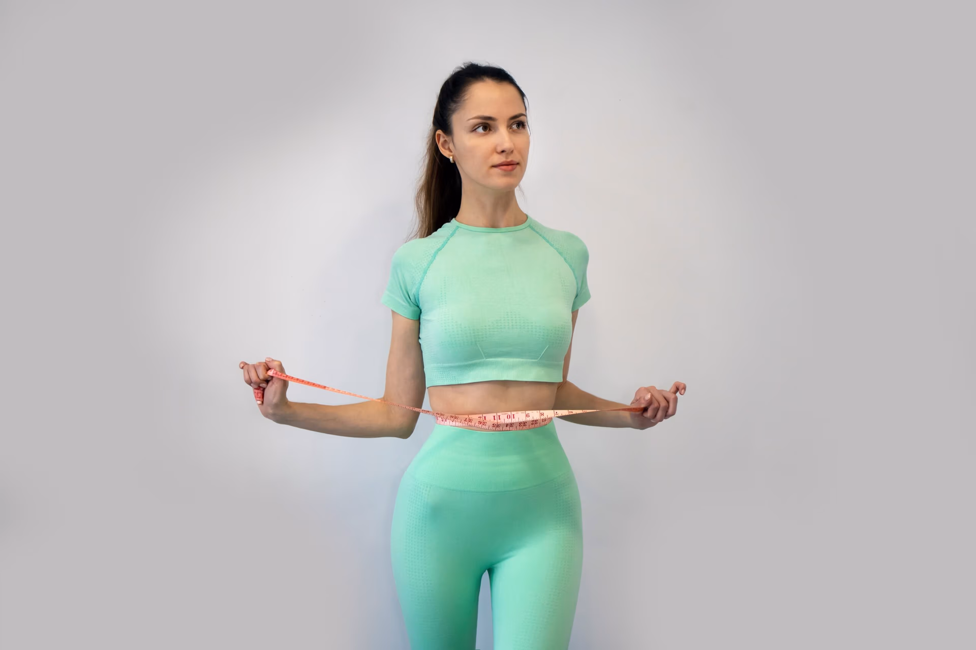Young Slender Woman In sportswear Measuring Her Waist Young Slender Woman In sportswear Measuring Her Waist